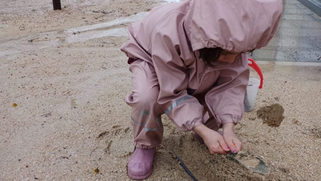 fotografía de una niña jugando en la lluvia con un conjunto impermeable