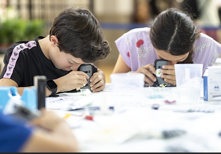 Dos escolares obsevando a través de un microscopio